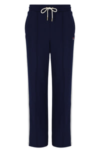 Navy blue wide-leg sweatpants with a white drawstring at the elastic waistband and white side stripes running down the legs, featuring a small red and white Fila logo on the left hip.