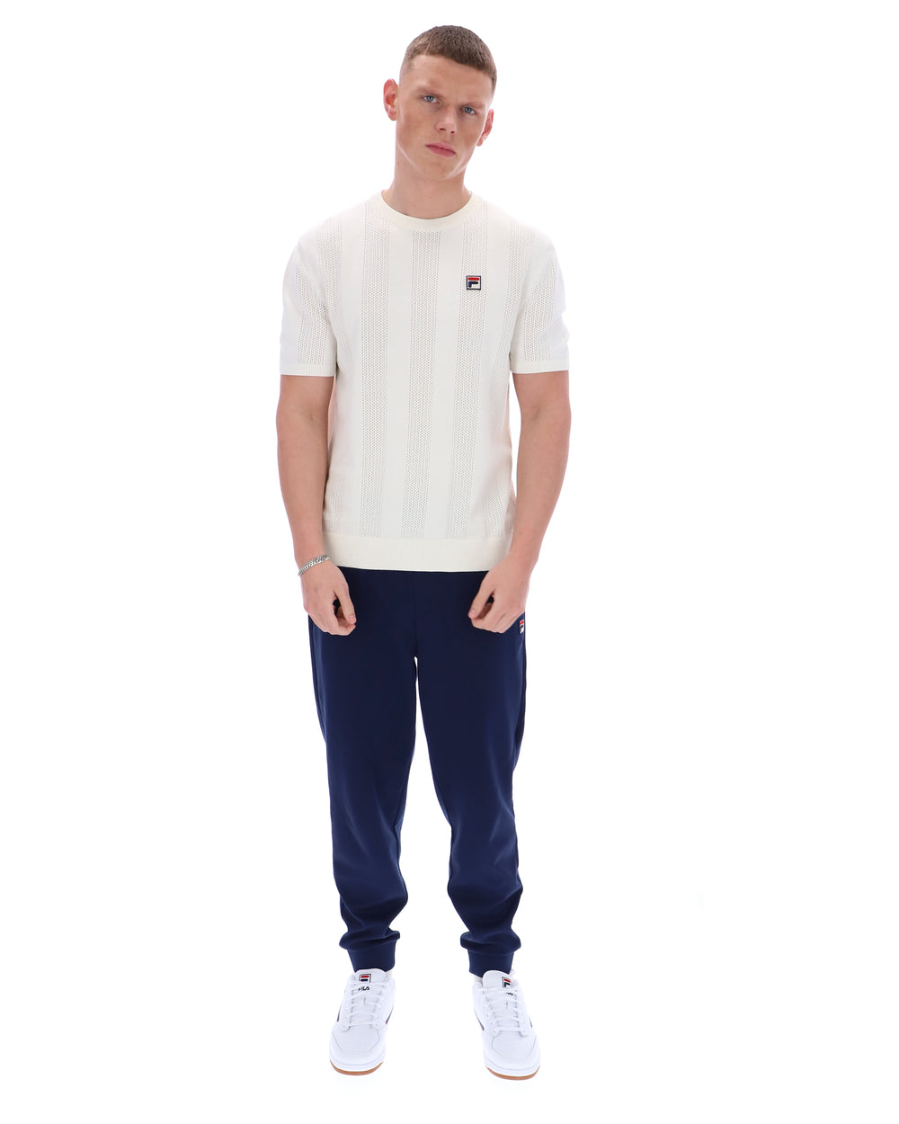 Man wearing a white t-shirt and navy tracksuit pants on a white background