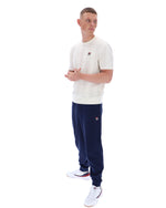 Man wearing a white t-shirt and navy tracksuit on a white background