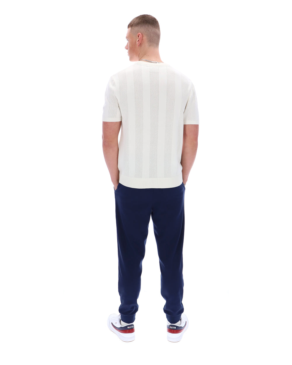 Man wearing a white t-shirt and navy pants on a white background