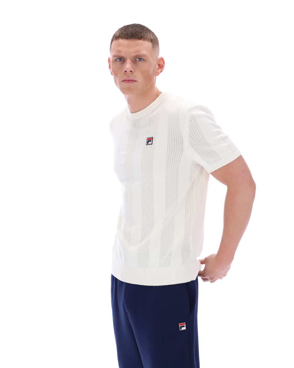 Man wearing a white t-shirt and navy pants with a visible brand logo on a white background