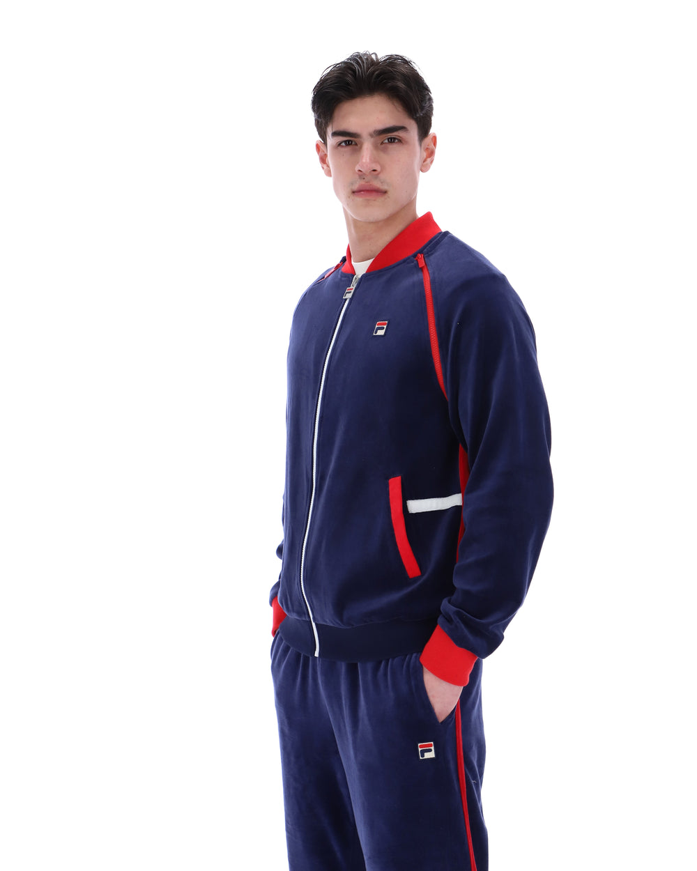 Man wearing a navy tracksuit with red accents on a white background