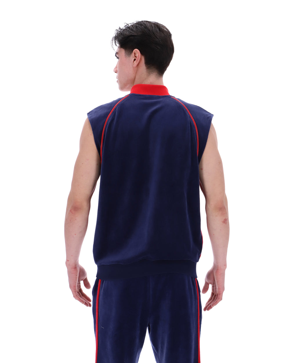 Person wearing a navy sleeveless shirt and pants with red accents on a white background