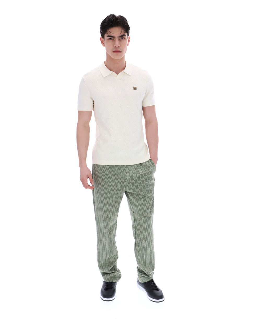 Man wearing a white polo shirt and green pants on a white background