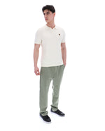 Man wearing a white polo shirt and green pants on a white background