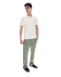 Man wearing a white polo shirt and green pants on a white background
