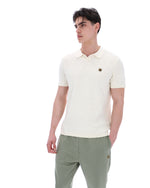Man wearing a white polo shirt and green pants on a white background