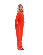 Woman wearing a bright red tracksuit on a white background