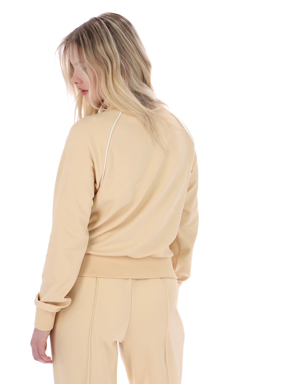 Woman wearing a beige tracksuit on a white background