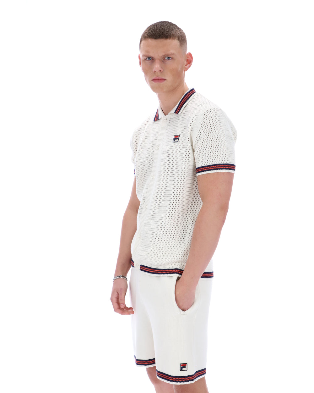 Man wearing a white textured polo shirt and shorts with red and blue trim on a white background
