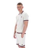 Man wearing a white textured polo shirt and shorts with red and blue trim on a white background
