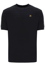 Black t-shirt with a small FILA Gold logo on the chest on a white background