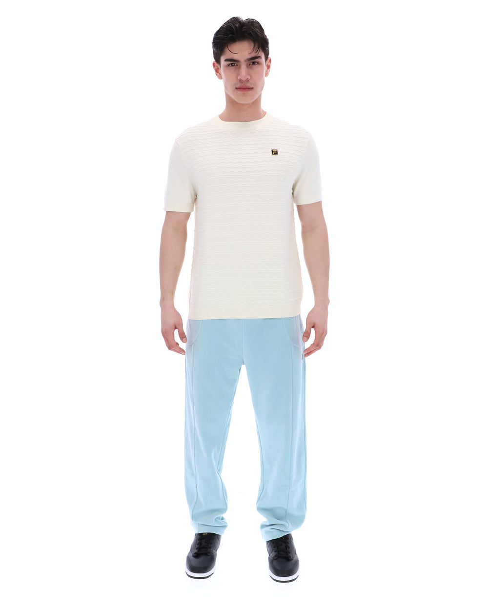 Man wearing a white t-shirt and light blue pants on a white background