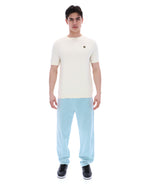 Man wearing a white t-shirt and light blue pants on a white background
