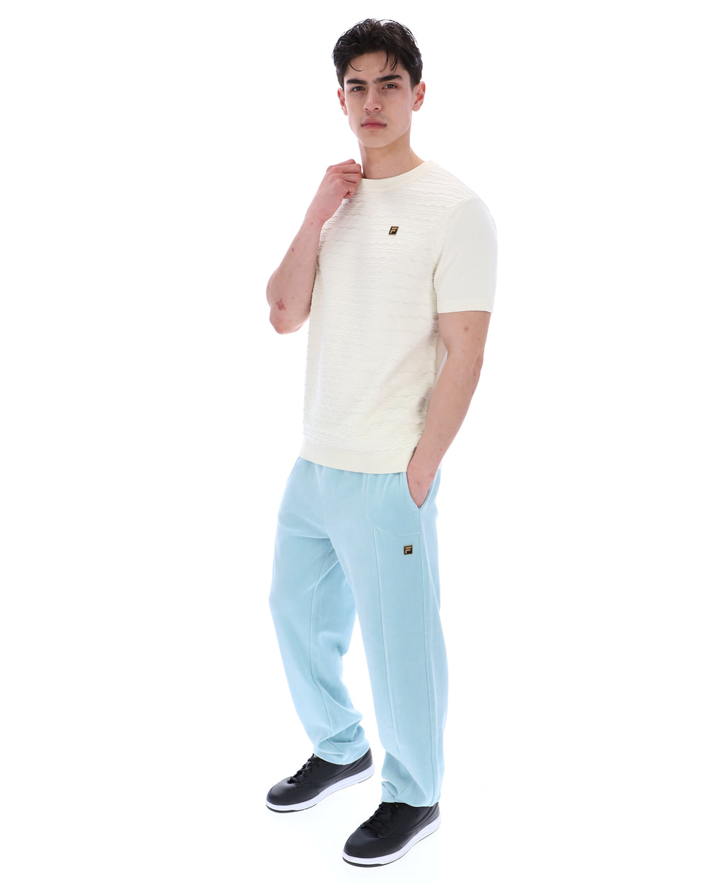 Man wearing a white t-shirt and light blue pants on a white background