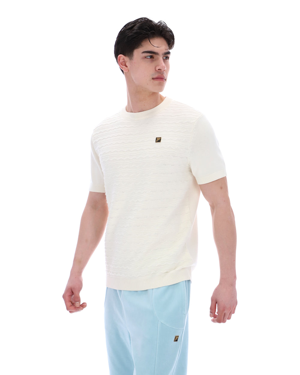 Man wearing a cream-coloured t-shirt with a small logo on a white background