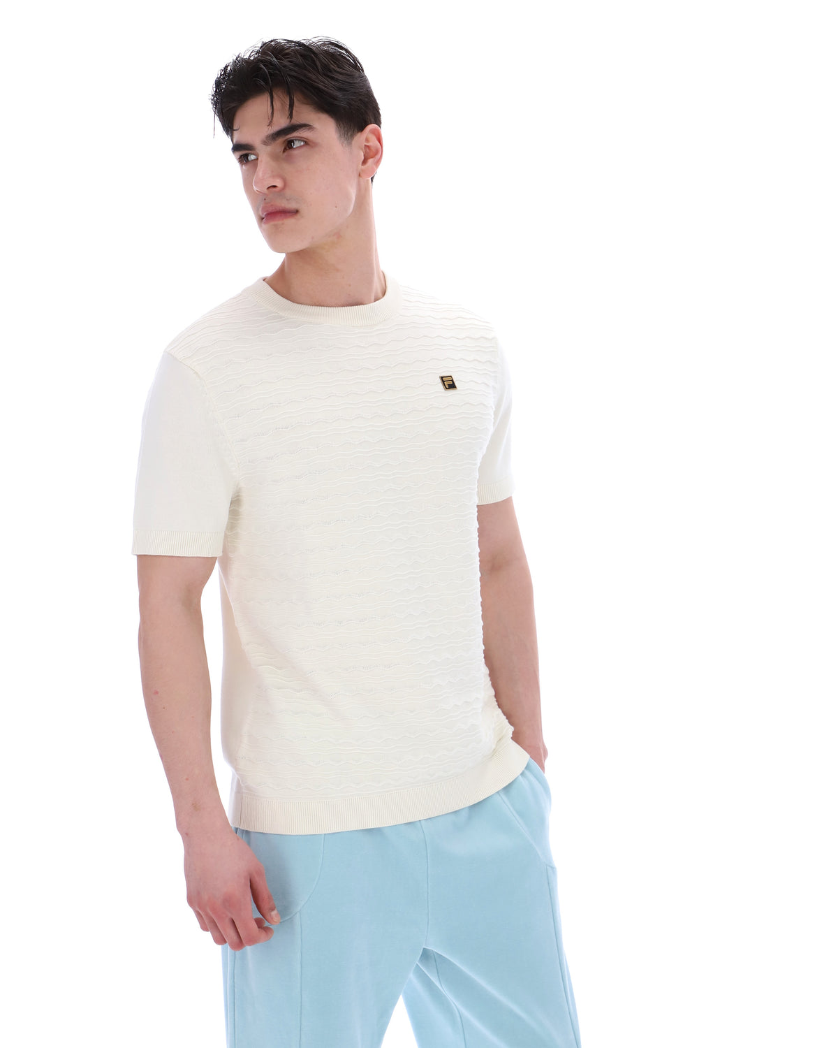 Man wearing a white t-shirt with a small logo and light blue pants on a white background