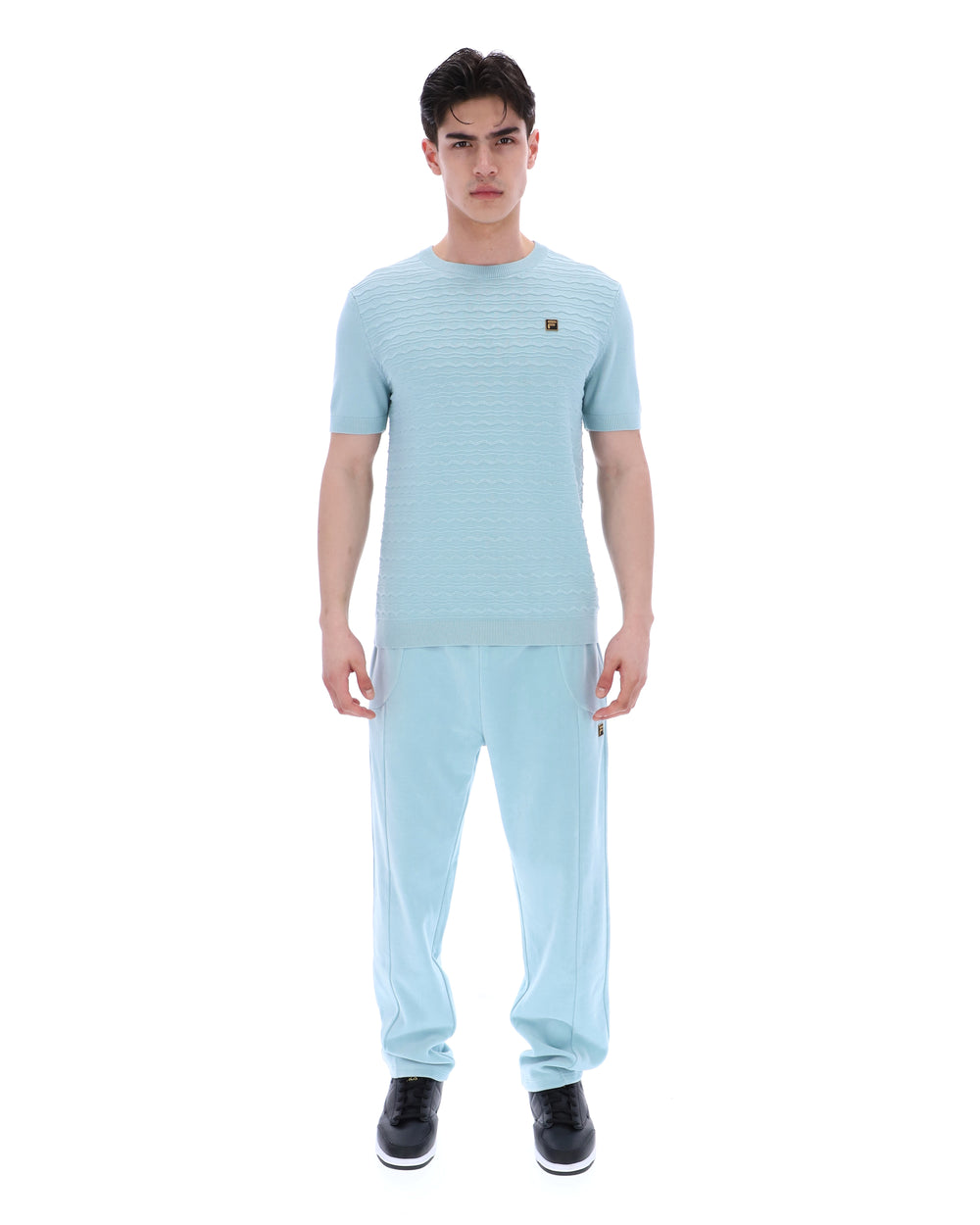 Man wearing a light blue outfit with a matching shirt and pants on a white background