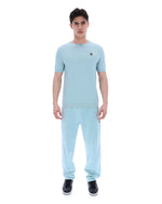 Man wearing a light blue outfit with a matching shirt and pants on a white background