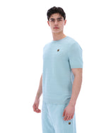 Man wearing a light blue textured t-shirt and pants on a white background