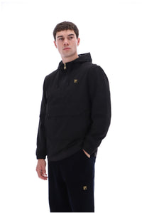 A man wearing a black pullover hoodie with a small gold logo on the chest, paired with black pants featuring a matching gold logo near the lower leg, set against a plain white background.