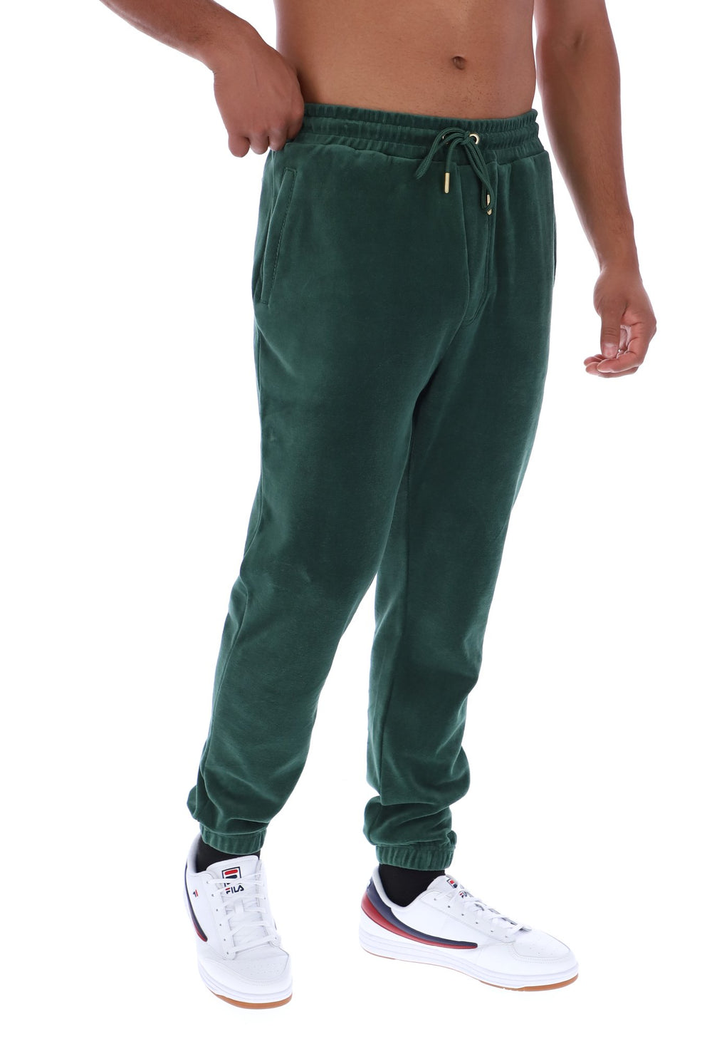 A person wearing dark green jogger sweatpants with a drawstring waist and elastic cuffs, paired with white sneakers, shown against a plain white background.