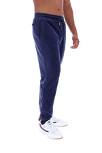 A side profile view of a person wearing navy blue jogger sweatpants and white sneakers, shown against a plain white background.