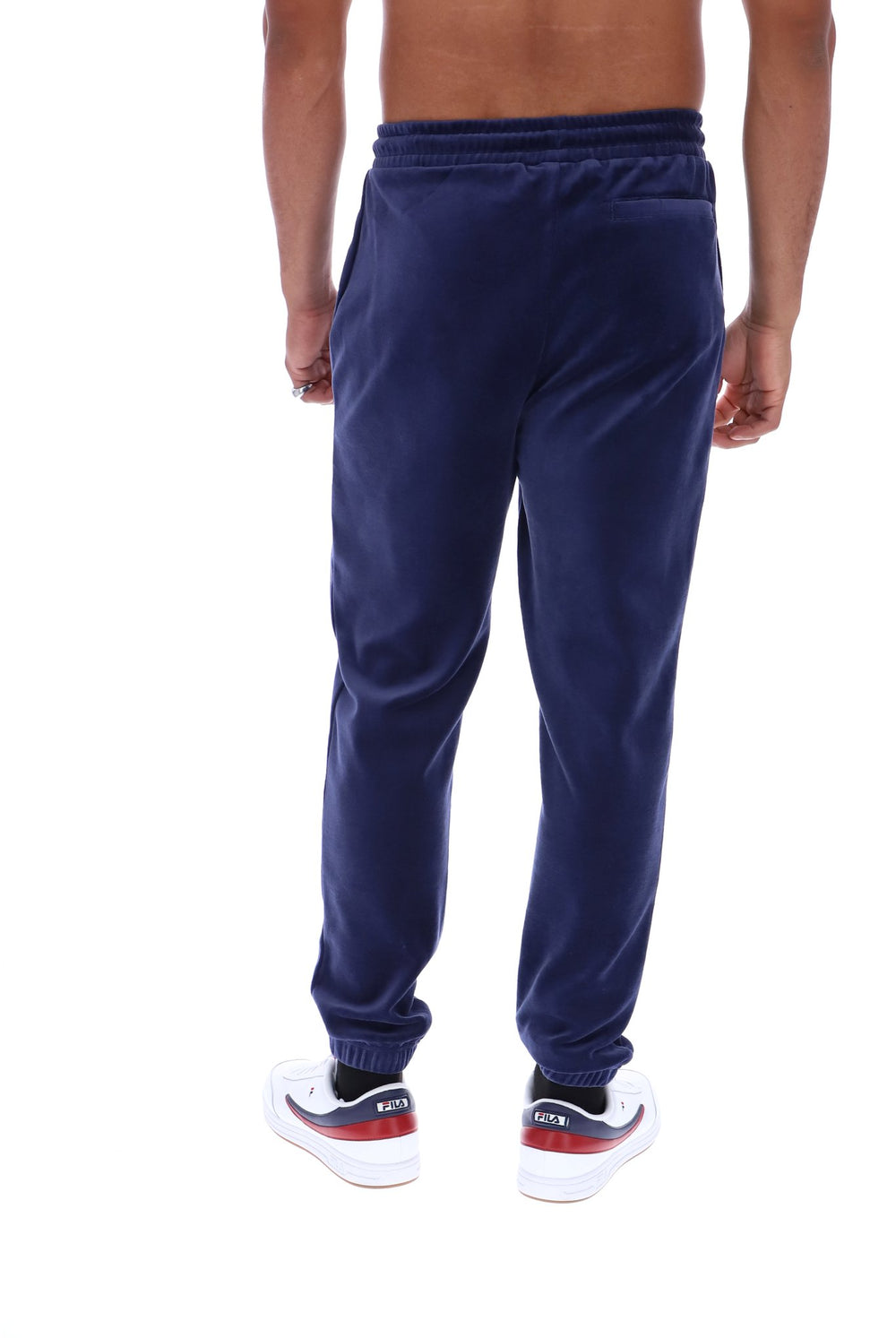 A person shown from the back wearing navy blue jogger sweatpants and white sneakers with red and black accents, against a plain white background.