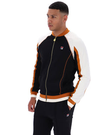 Man wearing a black, white, and orange tracksuit with a visible FILA logo on a white background