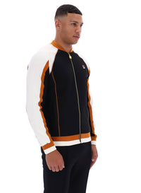 Man wearing a black, white, and orange tracksuit with a visible FILA logo on a white background