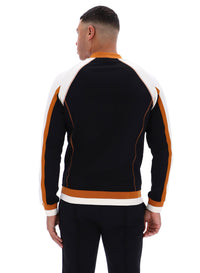 Person wearing a black tracksuit with orange and white accents on a white background