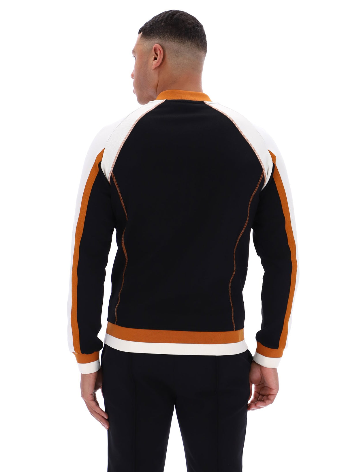Person wearing a black tracksuit with orange and white accents on a white background