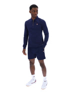 Man wearing a navy blue zip-up collared long-sleeve with a FILA logo on the chest, paired with matching shorts, on a white background