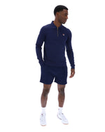 Man wearing a navy blue zip-up collared long-sleeve with a FILA logo on the chest, paired with matching shorts, on a white background