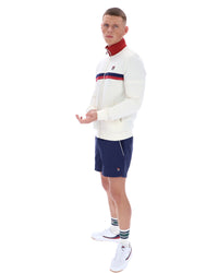 Man wearing a white sweater with red and blue accents and navy shorts on a white background