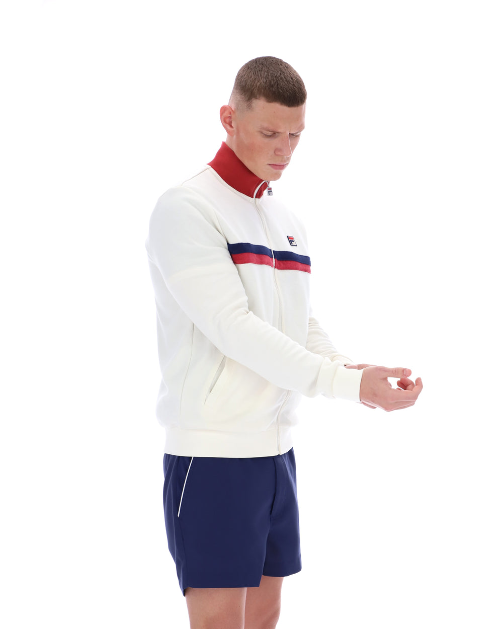 Man wearing a white jacket with red and blue accents and navy shorts on a white background
