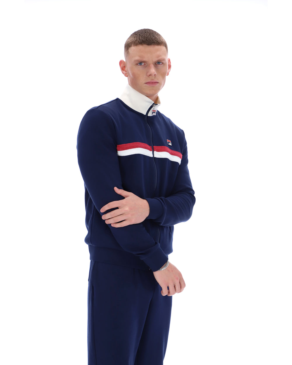 Man wearing a navy tracksuit with a white collar and red and white stripe on a white background