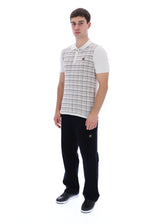 A man modeling a sleeveless polo shirt vest with a white and beige plaid pattern over white short-sleeve undershirts, paired with black trousers and black sneakers, against a plain white background.