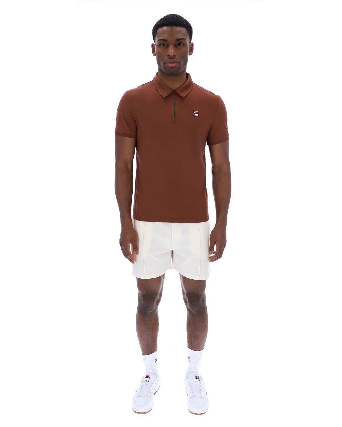 Man wearing a brown polo shirt and white shorts on a white background