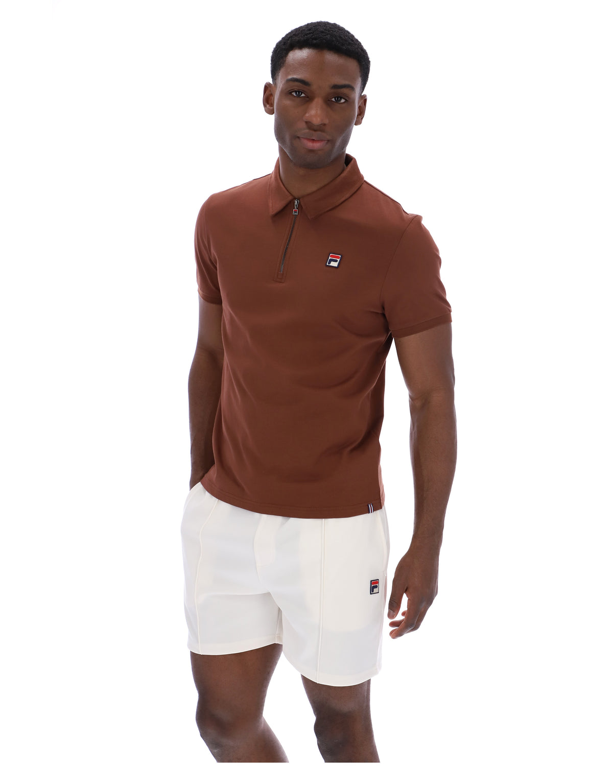 Man wearing a brown FILA polo shirt and white shorts with a FILA logo, against a white background
