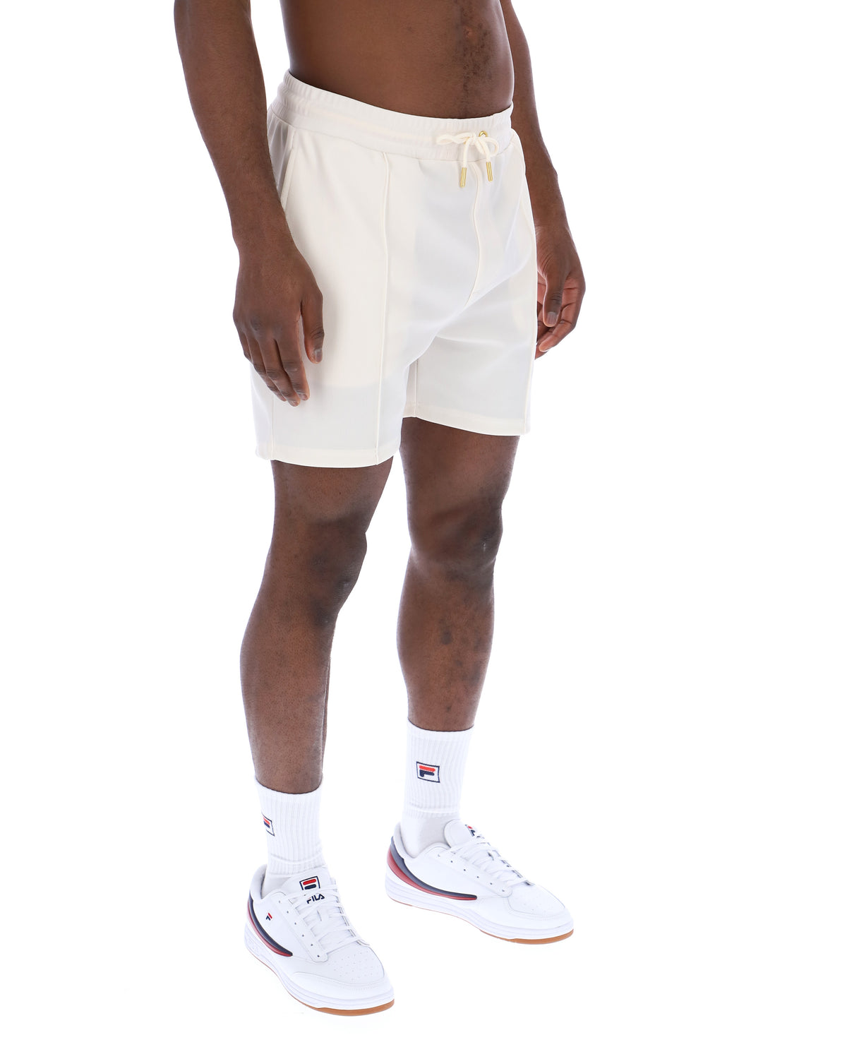 Displays a model wearing the Gardenia 'FILA' branded Eusebio Pin-Tuck Shorts