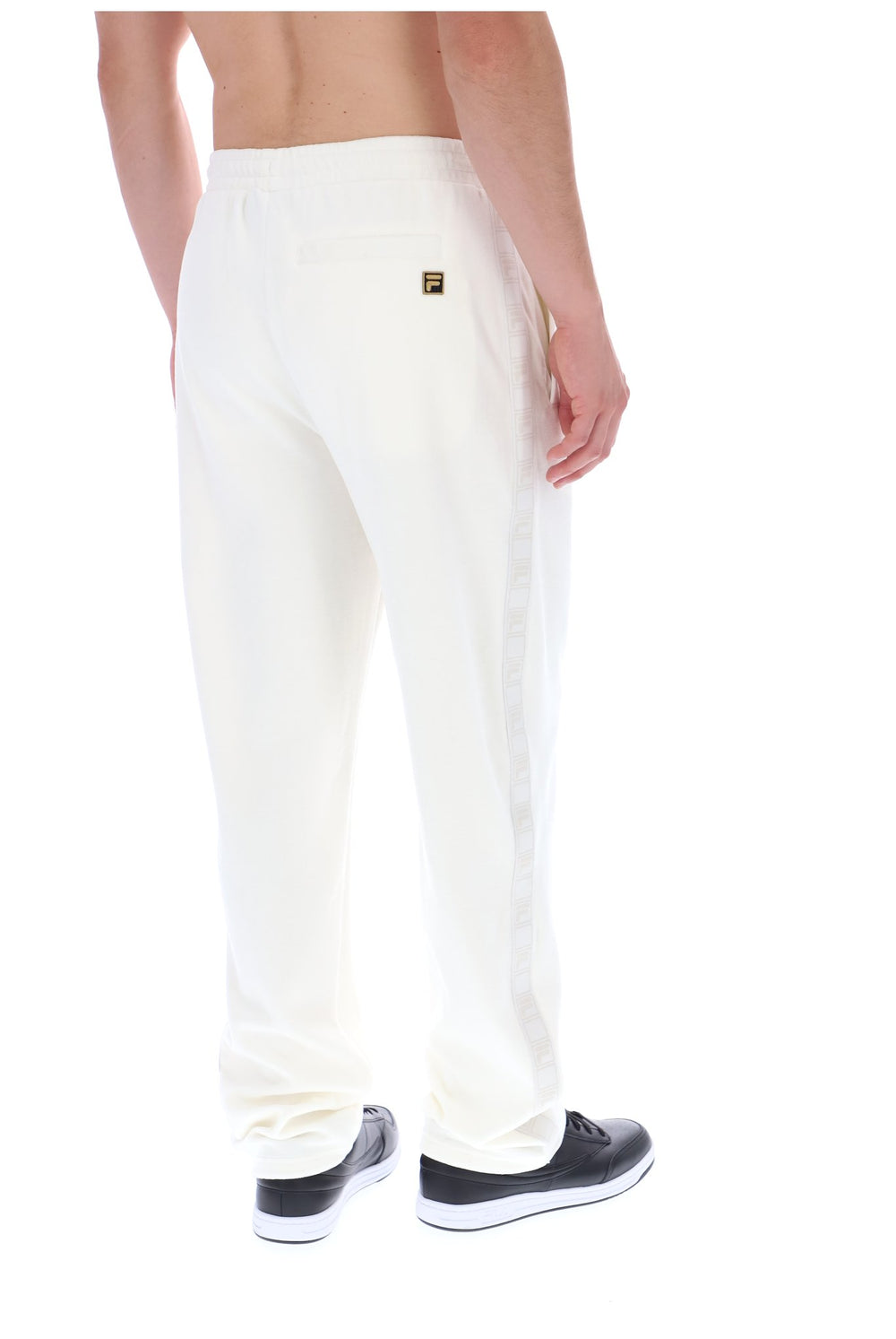 Displays a model wearing the White 'FILA' branded Down Fario Velour Track Pant