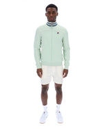 Man wearing a light green jacket with a FILA logo, white shorts, and white sneakers on a white background