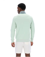 Man wearing a light green track jacket and white shorts on a white background
