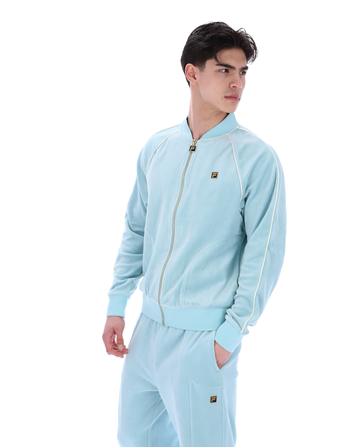 Man wearing a light blue tracksuit with a logo on a white background
