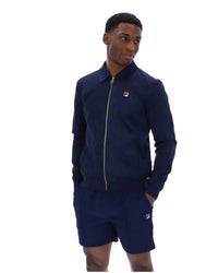 Man wearing a navy tracksuit jacket with a FILA logo on the chest, paired with matching shorts, on a white background