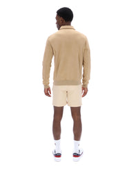 Man wearing a beige jacket and cream shorts on a white background