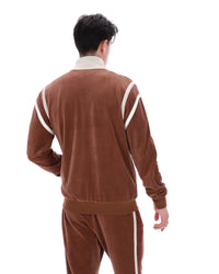 Man wearing a brown tracksuit with white stripes on a white background