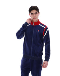 Man wearing a navy tracksuit with red and white accents, with a FILA logo on the chest, paired with matching bottoms, against a white background