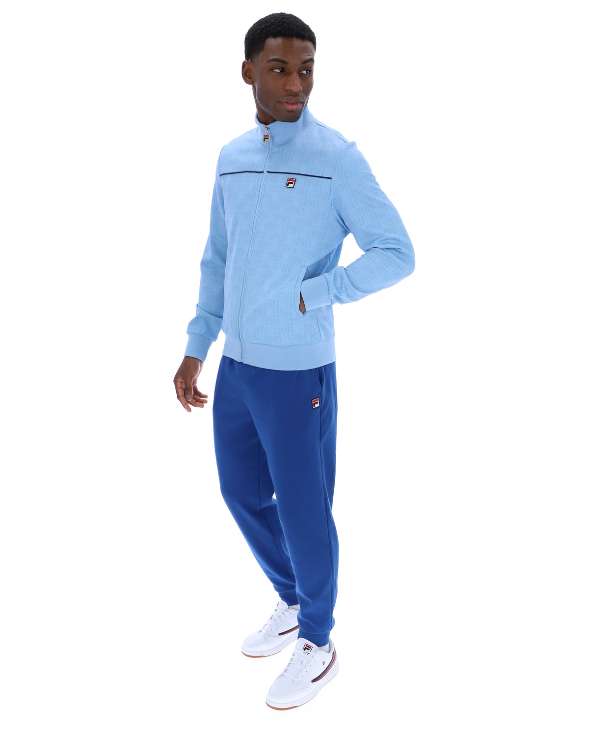 Man wearing a light blue tracksuit with a brand logo on a white background